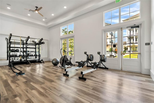 workout room with ceiling fan, hardwood / wood-style floors, and a towering ceiling