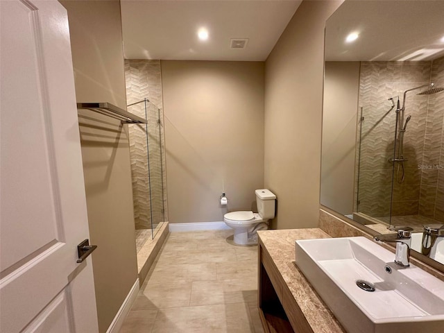 bathroom featuring tiled shower, tile patterned flooring, vanity, and toilet