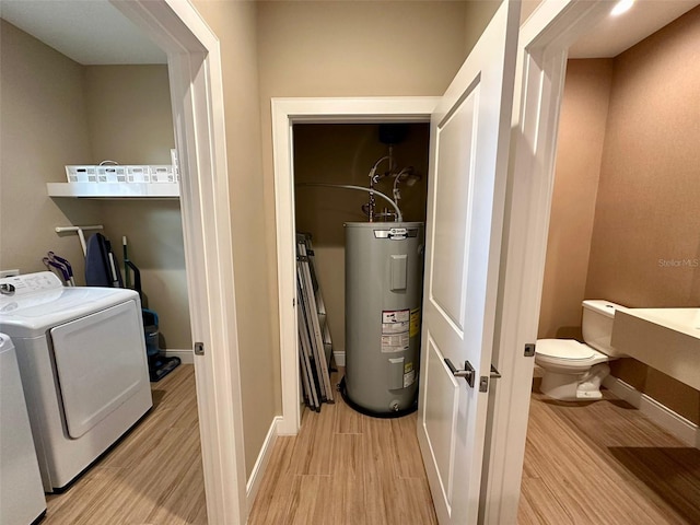 washroom with light wood-type flooring, washer and clothes dryer, and water heater