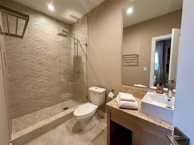 bathroom with tile patterned floors, vanity, toilet, and a tile shower