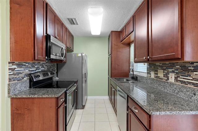 kitchen featuring decorative backsplash, appliances with stainless steel finishes, sink, light tile patterned floors, and dark stone countertops