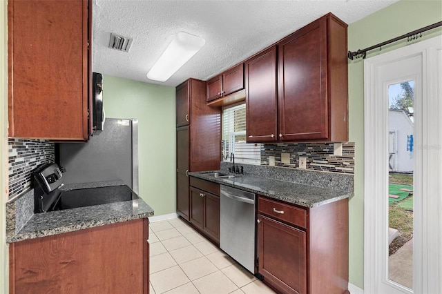 kitchen with dark stone countertops, sink, stainless steel appliances, and tasteful backsplash