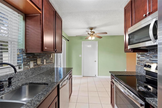 kitchen featuring sink, dark stone countertops, light tile patterned floors, tasteful backsplash, and stainless steel appliances