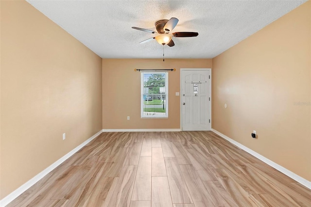 unfurnished room featuring ceiling fan, light wood-type flooring, and a textured ceiling