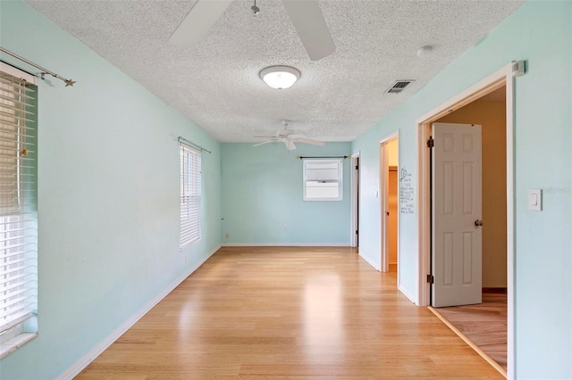 spare room with a textured ceiling, light wood-type flooring, and ceiling fan