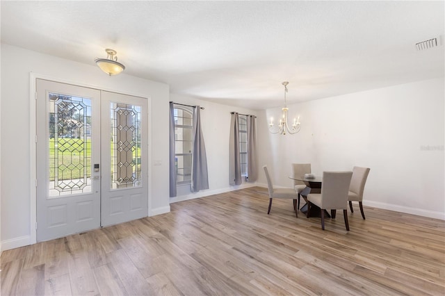 dining space with light wood-type flooring and a chandelier