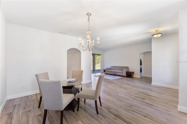 dining room with light hardwood / wood-style floors and a notable chandelier