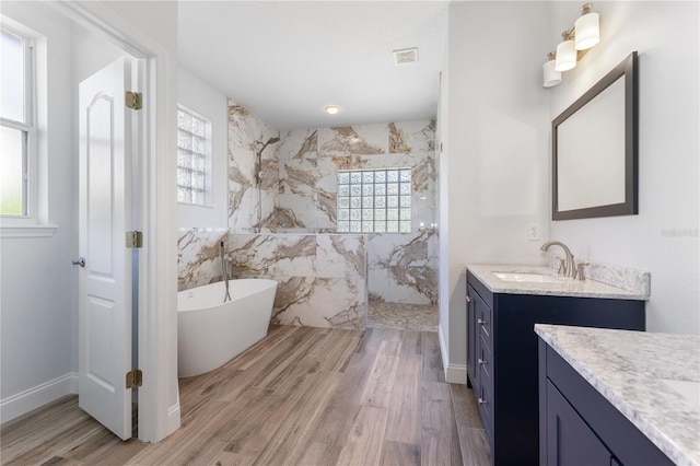 bathroom featuring hardwood / wood-style flooring, vanity, shower with separate bathtub, and tile walls