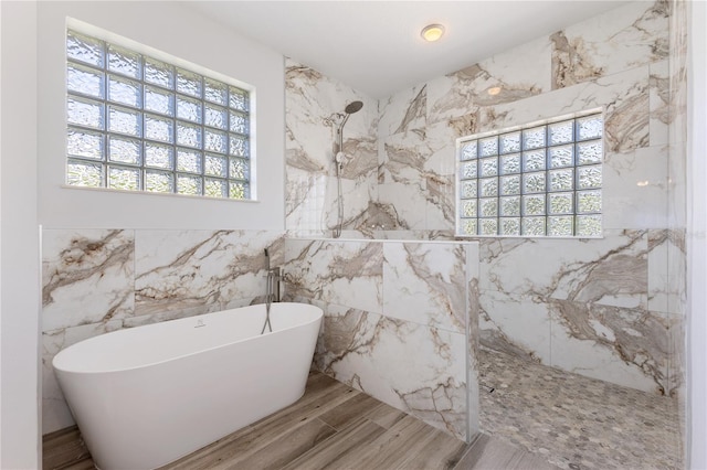 bathroom with wood-type flooring, shower with separate bathtub, and tile walls