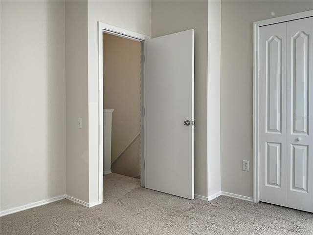 unfurnished bedroom featuring light carpet and a closet