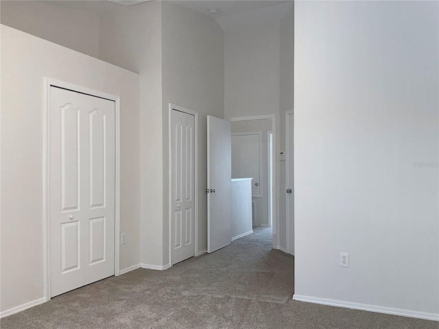 hallway featuring carpet flooring and a towering ceiling