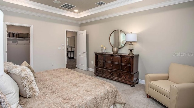 carpeted bedroom with a walk in closet, a tray ceiling, a closet, and crown molding