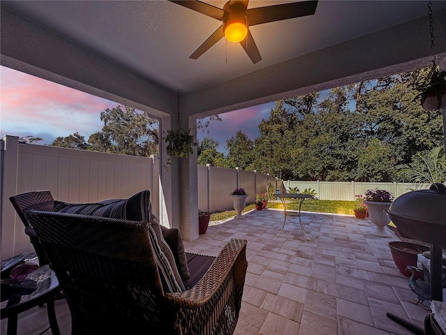 patio terrace at dusk featuring grilling area and ceiling fan