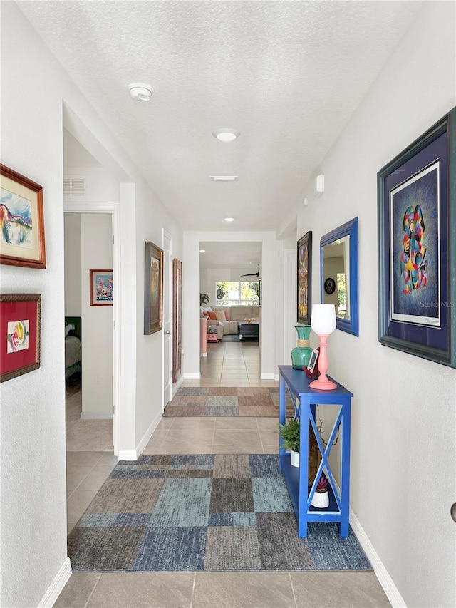 hall with tile patterned floors and a textured ceiling