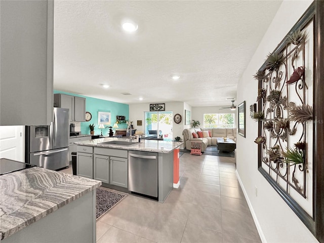 kitchen with gray cabinets, sink, an island with sink, and appliances with stainless steel finishes