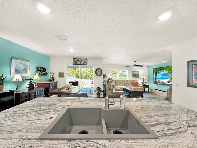 kitchen featuring a textured ceiling, ceiling fan, and sink