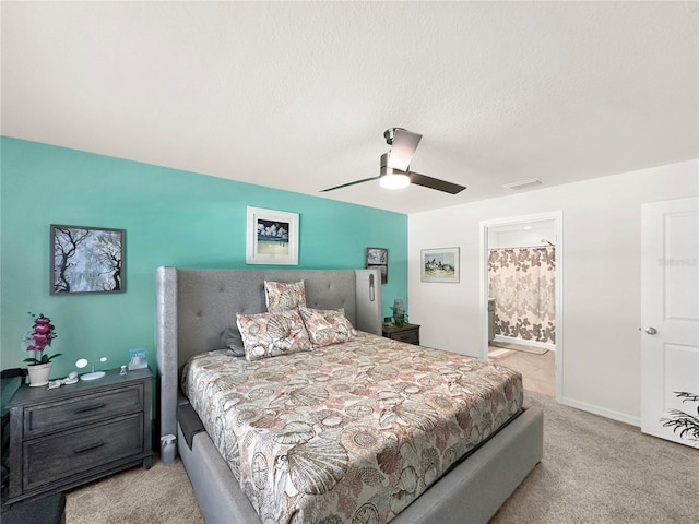 carpeted bedroom with a textured ceiling, ensuite bathroom, and ceiling fan