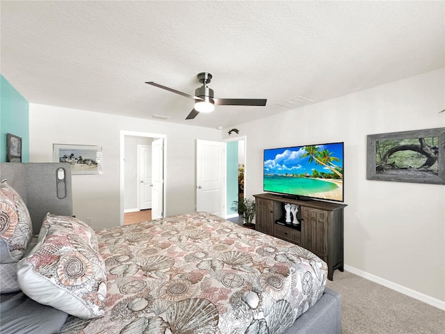 bedroom featuring a textured ceiling, light colored carpet, and ceiling fan