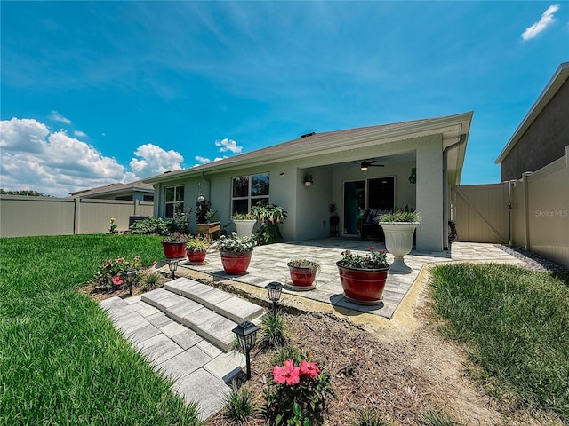 7729 Rosewood Garden Loop, Tampa, FL 33637 - back of property featuring ceiling fan, a gate, a patio area, stucco siding, and a fenced backyard