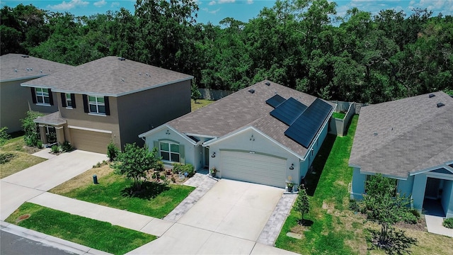 7729 Rosewood Garden Loop, Tampa, FL 33637 - view of front facade featuring driveway, stucco siding, solar panels, roof with shingles, and a front lawn