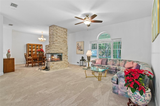 living room with a stone fireplace, carpet floors, and ceiling fan with notable chandelier