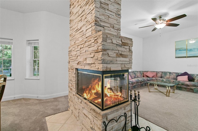 carpeted living room featuring a stone fireplace and ceiling fan