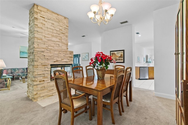 dining area featuring a stone fireplace, light carpet, and a chandelier