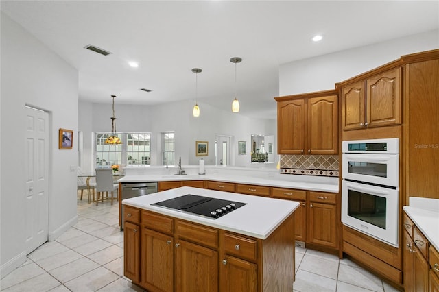 kitchen with sink, white double oven, hanging light fixtures, a kitchen island, and electric stovetop