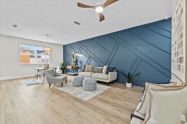 living room featuring ceiling fan with notable chandelier and light hardwood / wood-style floors