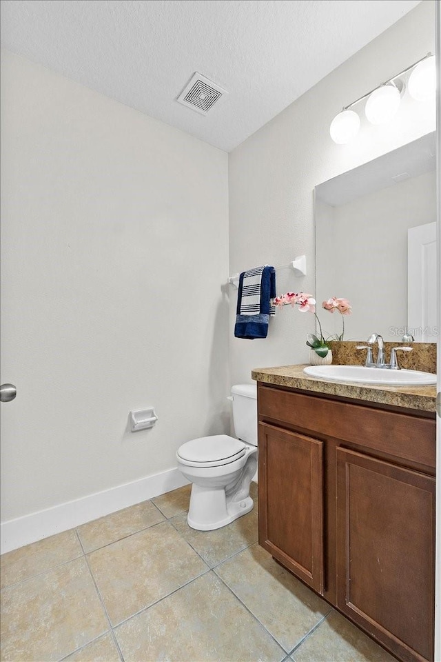 bathroom with toilet, vanity, a textured ceiling, and tile patterned floors