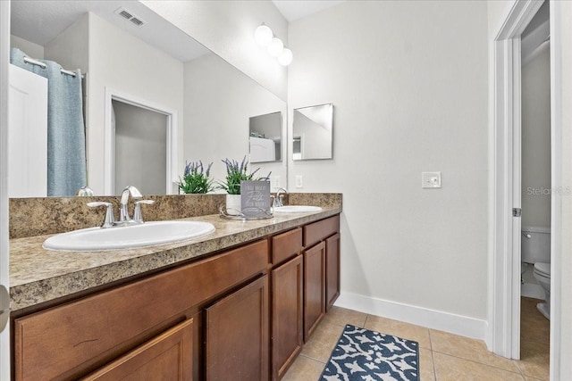 bathroom with toilet, vanity, and tile patterned floors