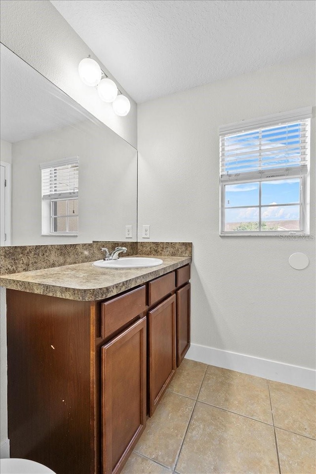 bathroom with tile patterned flooring, vanity, and a textured ceiling