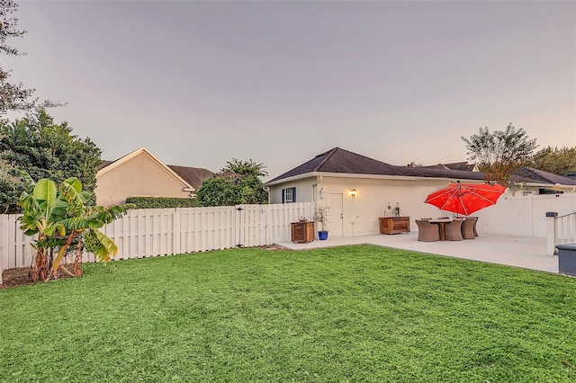 yard at dusk featuring a patio