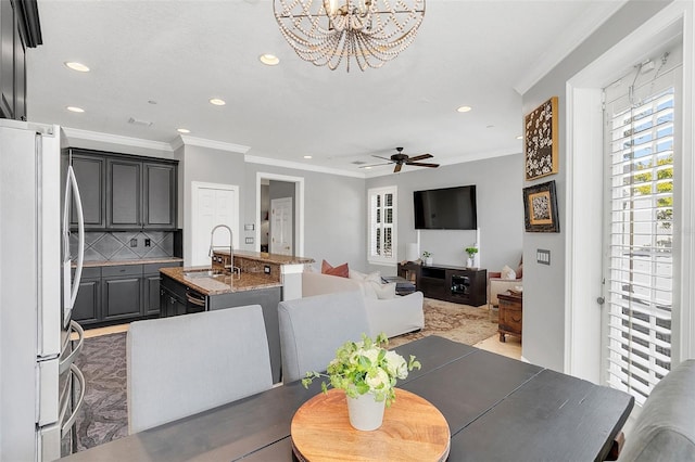 dining space featuring sink, ornamental molding, and ceiling fan with notable chandelier