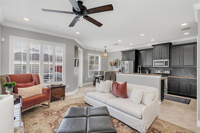 tiled living room featuring ceiling fan, crown molding, and sink