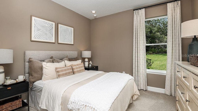 bedroom with light colored carpet, a textured ceiling, and multiple windows