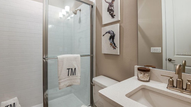 bathroom featuring vanity, toilet, and a shower with shower door