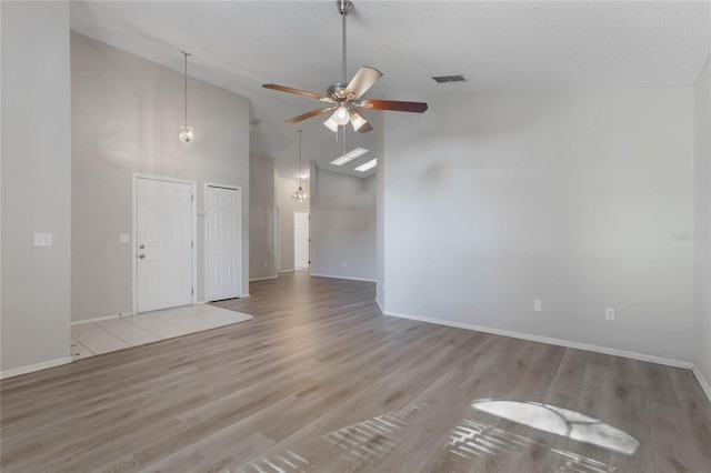 unfurnished room featuring a textured ceiling, light wood-type flooring, high vaulted ceiling, and ceiling fan