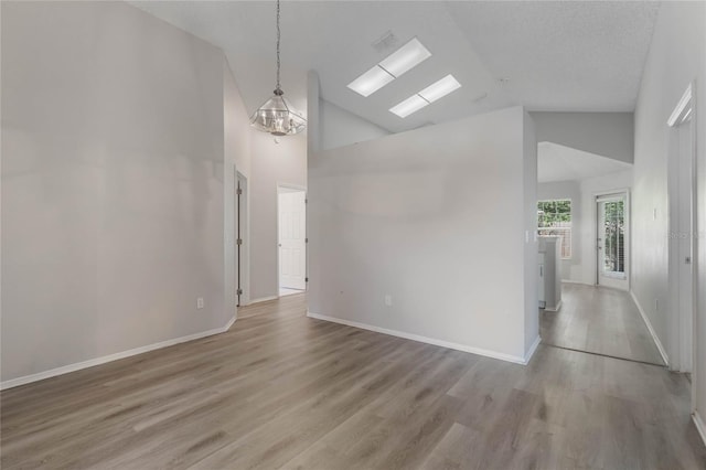 empty room featuring wood-type flooring, a textured ceiling, and high vaulted ceiling