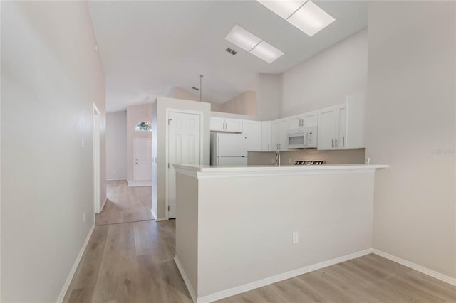 kitchen featuring light hardwood / wood-style flooring, high vaulted ceiling, kitchen peninsula, white appliances, and white cabinets