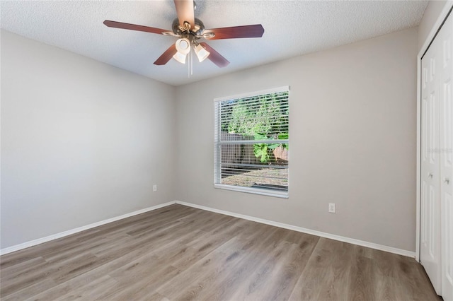 spare room featuring ceiling fan, light wood-type flooring, and a textured ceiling