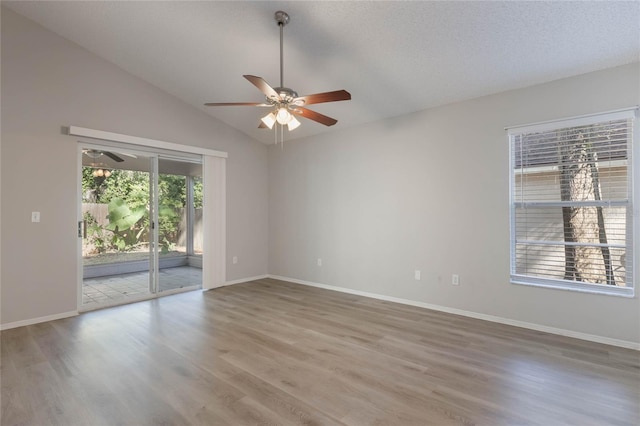 empty room with a textured ceiling, hardwood / wood-style flooring, vaulted ceiling, and ceiling fan