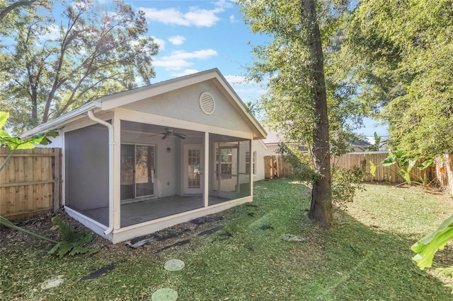 rear view of house with a sunroom, ceiling fan, and a lawn