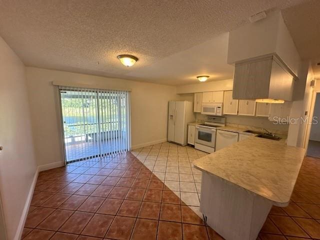 4518 Watch Hill Rd, Orlando, FL 32808 - kitchen with white appliances, light tile patterned flooring, light countertops, a textured ceiling, and white cabinets