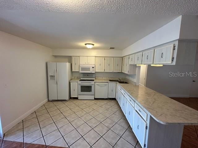 4518 Watch Hill Rd, Orlando, FL 32808 - kitchen featuring white appliances, light countertops, light tile patterned floors, a peninsula, and white cabinetry
