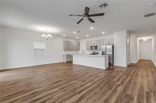 unfurnished living room featuring ceiling fan with notable chandelier, sink, and dark wood-type flooring