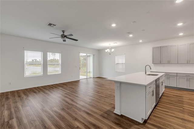 kitchen featuring ceiling fan with notable chandelier, a kitchen island with sink, dark wood-type flooring, and sink