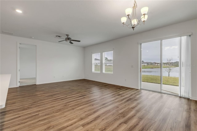 empty room with hardwood / wood-style floors, a water view, and ceiling fan with notable chandelier