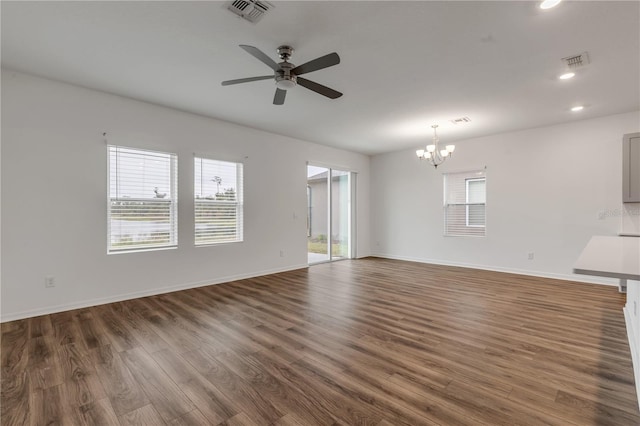 unfurnished living room with dark wood-type flooring and ceiling fan with notable chandelier