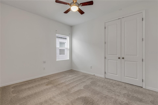 unfurnished bedroom with a closet, light colored carpet, and ceiling fan